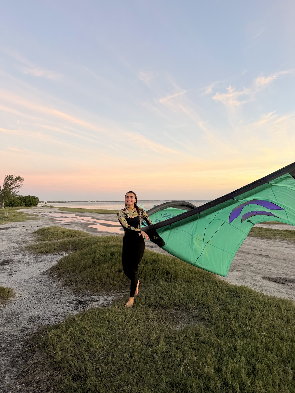 Gabi com o kite ao entardecer na beira da lagoa