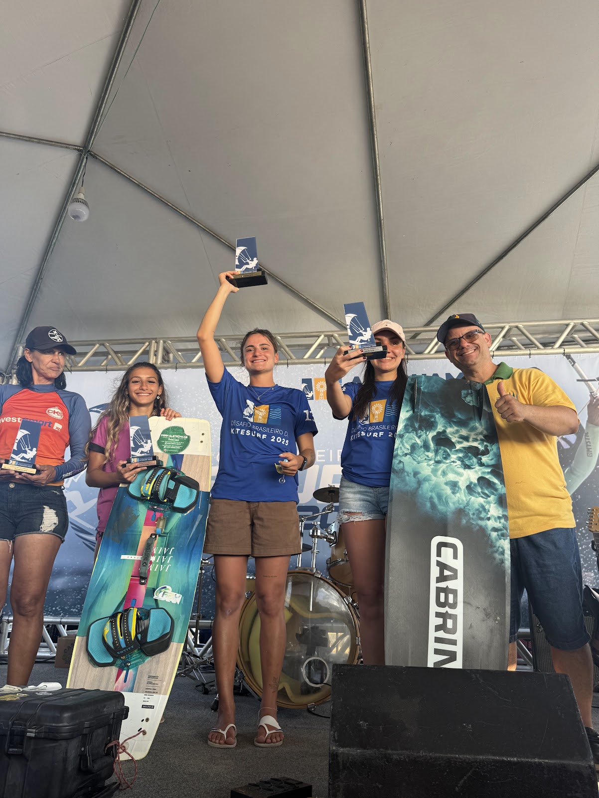 Gabi no pódio segurando troféu em campeonato de kitesurf
