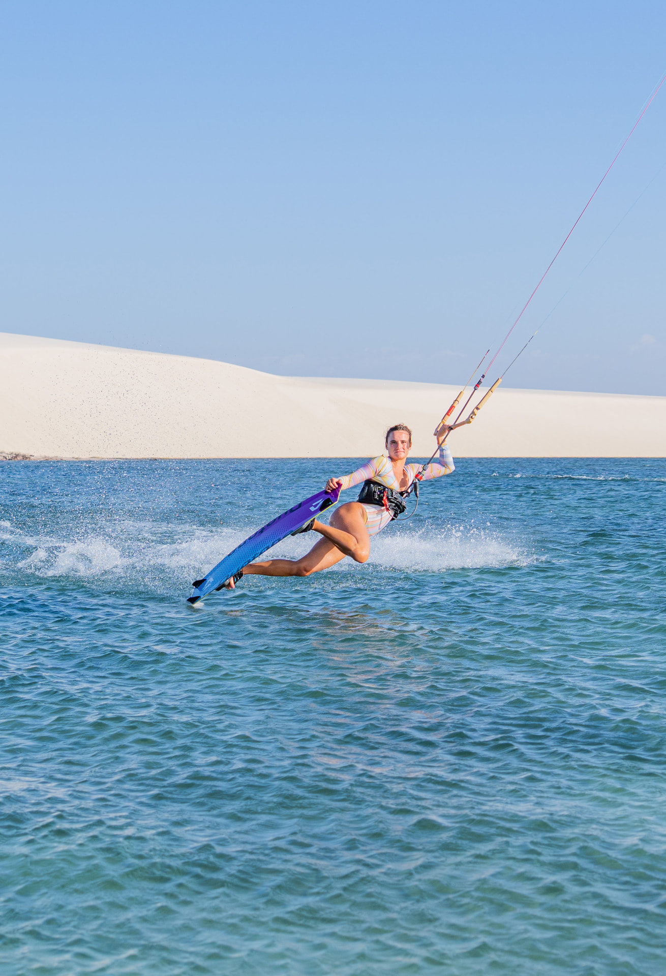 Gabi de kitesurf rasgando a água em frente às dunas dos Lençóis
